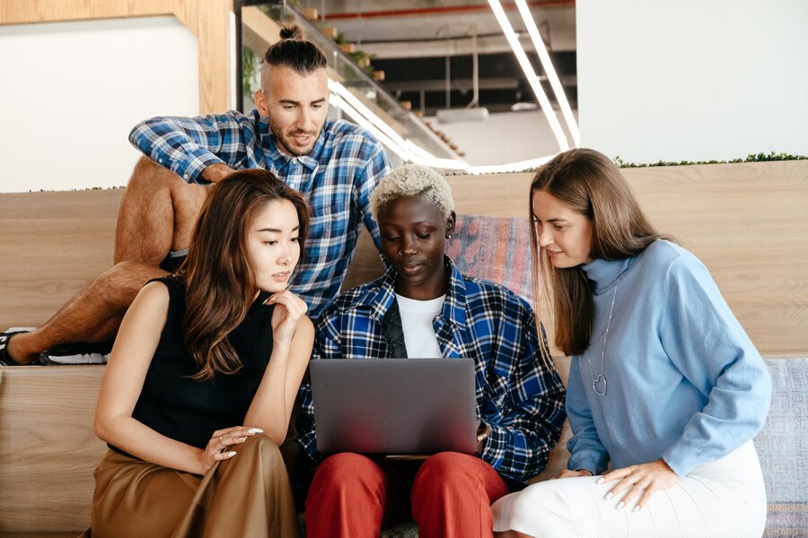 Friends gathered around a laptop discussing how to choose the right software outsourcing company